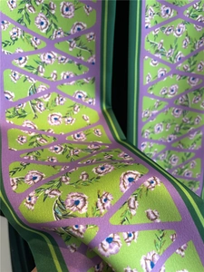 Détail d'un foulard étroit en satin vert et violet avec motifs floraux et géométriques