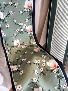 Détail de l'imprimé magnolia et des motifs géométriques sur une écharpe en soie vert foncé
