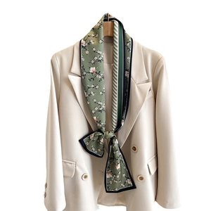 Foulard étroit en soie verte à fleurs noué sur un col de costume avec revers géométrique