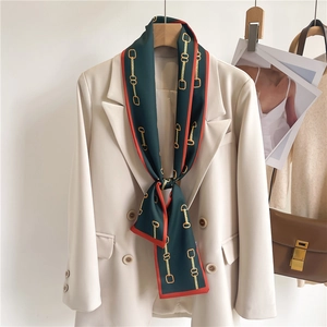Detail of silk scarf with gold chain print draped on a white double-breasted blazer