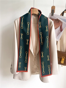 Detail of vintage pattern silk scarf styled on a beige blazer with chain and buckle print