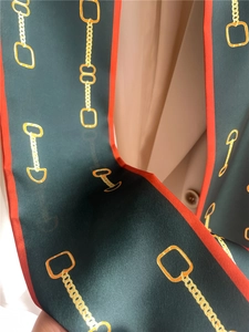 Macro view of dark green silk scarf with golden chain horsebit print on beige suit