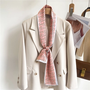 Pink narrow silk scarf with horsebit print tied on a chic white blazer for women
