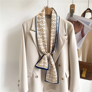 Detail of silk satin scarf with gold chain print styled on a beige double-breasted blazer
