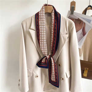 Elegant chain print skinny silk scarf tied on a beige blazer with professional styling