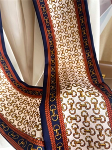 Detail of horsebit chain pattern on navy and orange silk headband scarf texture