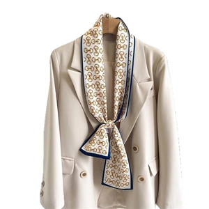 Long silk scarf with gold horsebit chain print and blue trim on beige blazer