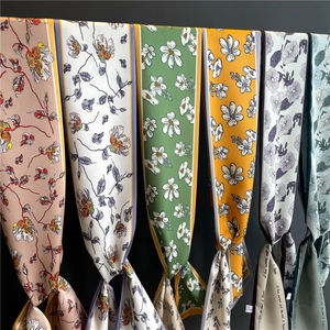Detailed view of narrow floral silk scarves with elegant hand-painted patterns on dark background