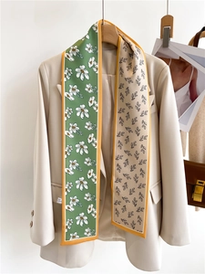 Detail of double-sided floral silk scarf on a beige suit with orange hem accents