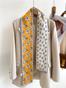Detailed close-up of a double-sided floral skinny scarf draped on a chic cream blazer