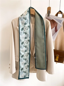 Vertical silk twilly with floral print and lettering styled on a beige blazer