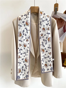 Detail of floral printed narrow silk scarf styled elegantly on a beige blazer