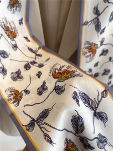 Detailed macro view of floral print silk scarf featuring purple blossoms and elegant edges