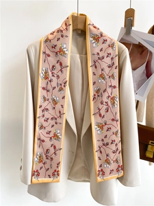 Detailed view of floral silk scarf styled on a beige blazer with yellow piping