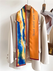 Écharpe en soie aux motifs abstraits bleus et orange stylisée sur un blazer beige