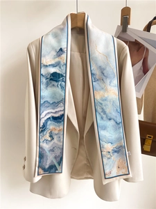 Écharpe étroite en soie à imprimé marbre bleu stylisée sur un revers de veste beige