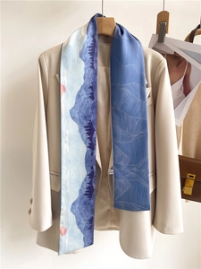 Détail d'un foulard en soie à motif paysage sur un tailleur beige aux tons bleutés