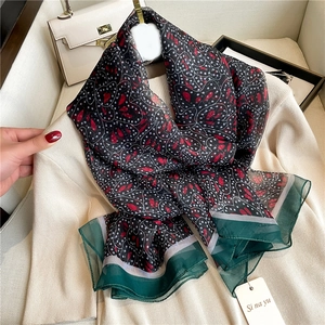 Floral silk-like scarf with heart patterns and chiffon edges on beige knitwear