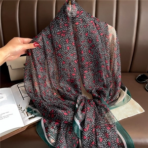Detail of elegant floral silk scarf featuring red heart patterns and green border
