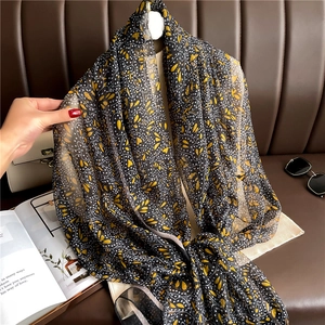 Detail showing sheer floral scarf with delicate yellow blossoms on black chiffon fabric