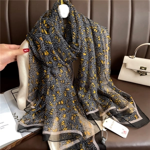 Detail of floral printed scarf with yellow leaf pattern and white polka dots on black