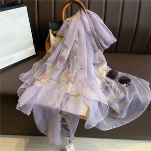 Detail of light purple silk scarf with floral pattern draped on a designer handbag
