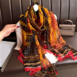 Large soft silk scarf with orange and yellow polka dots draped on a mannequin