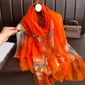 Detailed view of orange floral silk shawl with bird patterns and semi-transparent texture