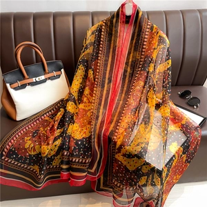 Detailed view of large bohemian floral silk shawl draped over a leather sofa
