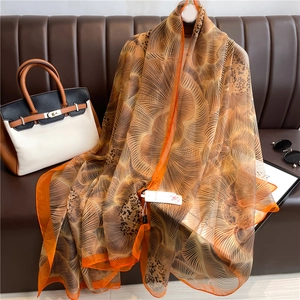 Luxurious large floral print silk scarf in warm brown and orange for elegant sun protection