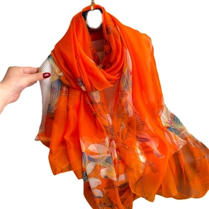 Elegant orange silk scarf with delicate floral and bird print on white background