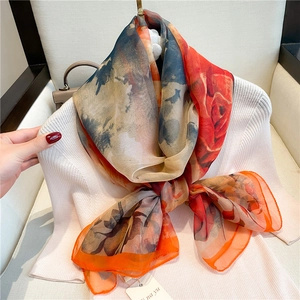 Close-up of lightweight floral silk scarf with vibrant red and orange flower patterns