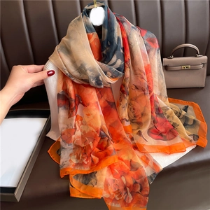 Close-up of orange floral faux silk shawl with large rose print on lightweight fabric