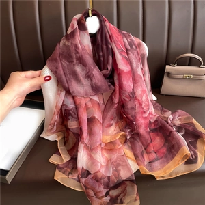 Macro detail of large floral silk scarf showing transparent fabric texture and fine hems