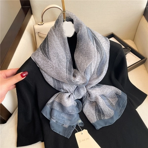 Elegant floral print shawl in grey and blue gradient displayed on a chic black sweater