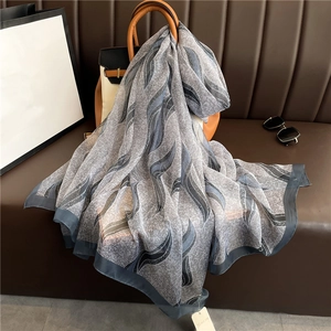 Elegant silk-like shawl with blue abstract pattern draped over a luxury leather handbag
