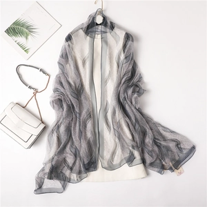 Detailed view of lightweight grey leaf-patterned shawl on a white dress