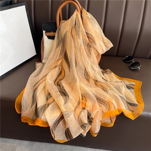 Detailed view of lightweight silk shawl with abstract orange leaf pattern on a handbag