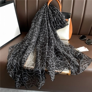 Detailed view of long rose pattern scarf draped over a stylish designer handbag