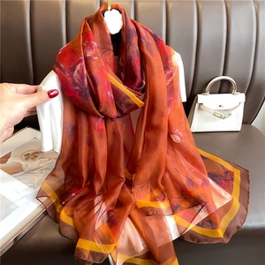 Detail of elegant large silk scarf with abstract floral pattern in retro red and brown