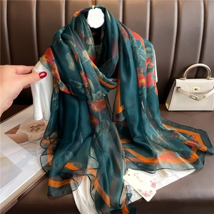 Detail of elegant dark green silk scarf with floral patterns and luxury sheer texture