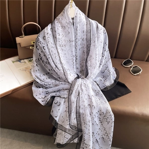 Detail of soft moon pattern scarf draped on leather chair with stylish accessories
