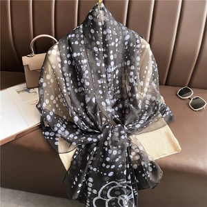 Detailed view of polka dot silk scarf with camellia motif on a knit sweater