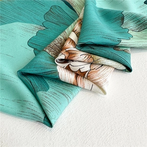 Close-up of mint green floral silk scarf with fine twill texture and soft glossy finish