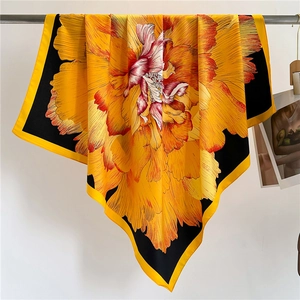 Detailed drape of large square silk scarf with vibrant orange and yellow floral print