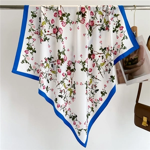 Detailed drape of floral silk scarf with pink roses and vivid royal blue border