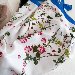 Close-up of floral silk scarf with pink roses and cobalt blue border details