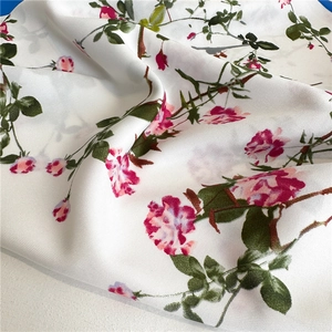 Detailed view of white floral silk scarf with pink roses and elegant soft drapes