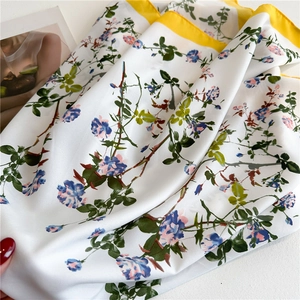 Detail of floral silk scarf showing light blue flowers and lemon yellow border