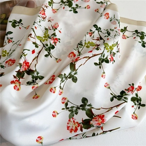 Detailed view of floral silk scarf featuring realistic red roses and golden borders